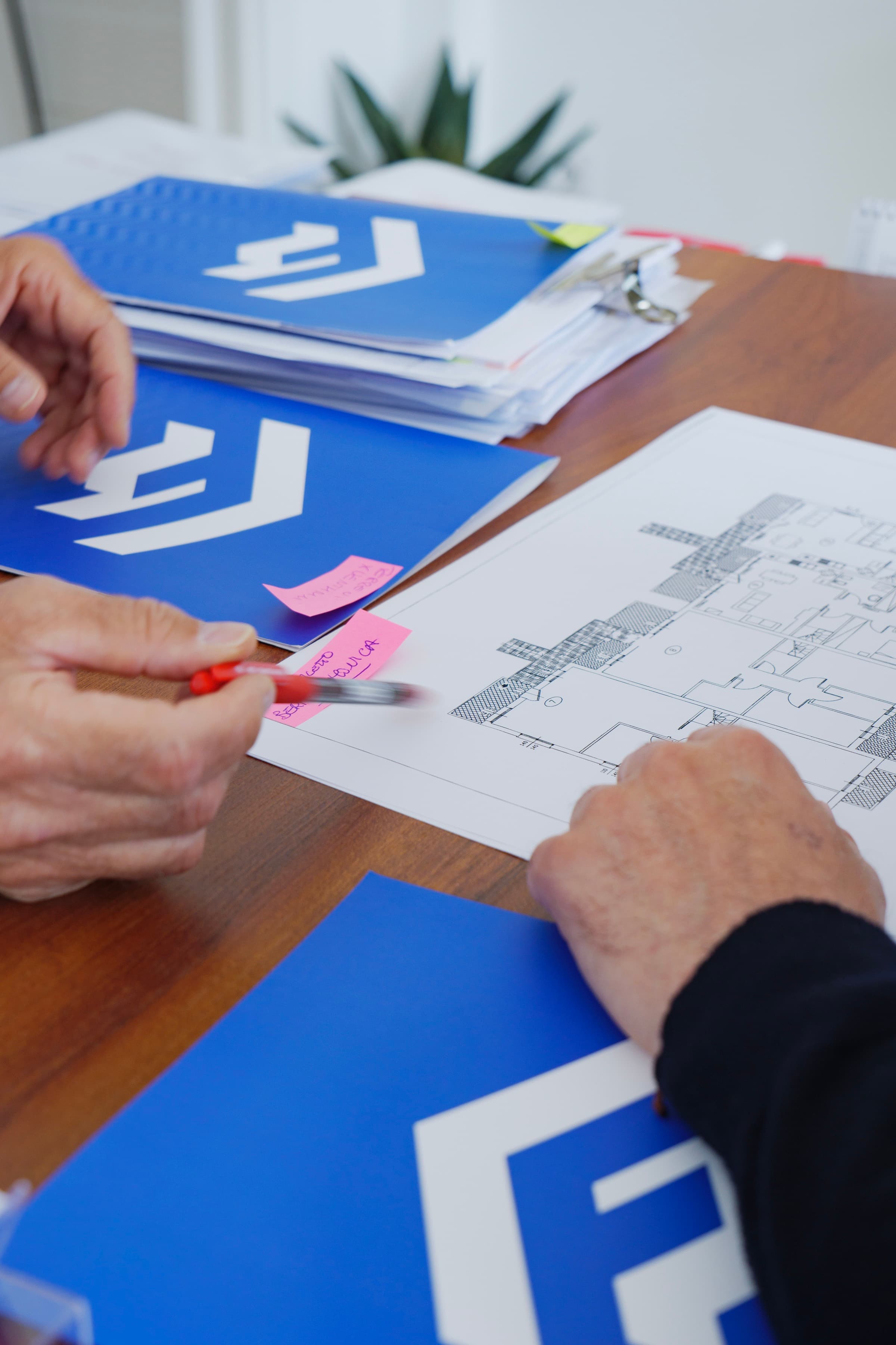 Dettaglio di una consulenza immobiliare con planimetrie e documenti sul tavolo